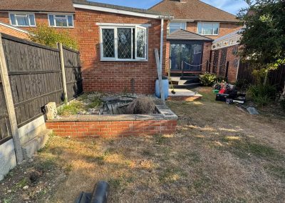 Garden before landscaping Braintree - bare patchy lawn and unfinished brick pond feature